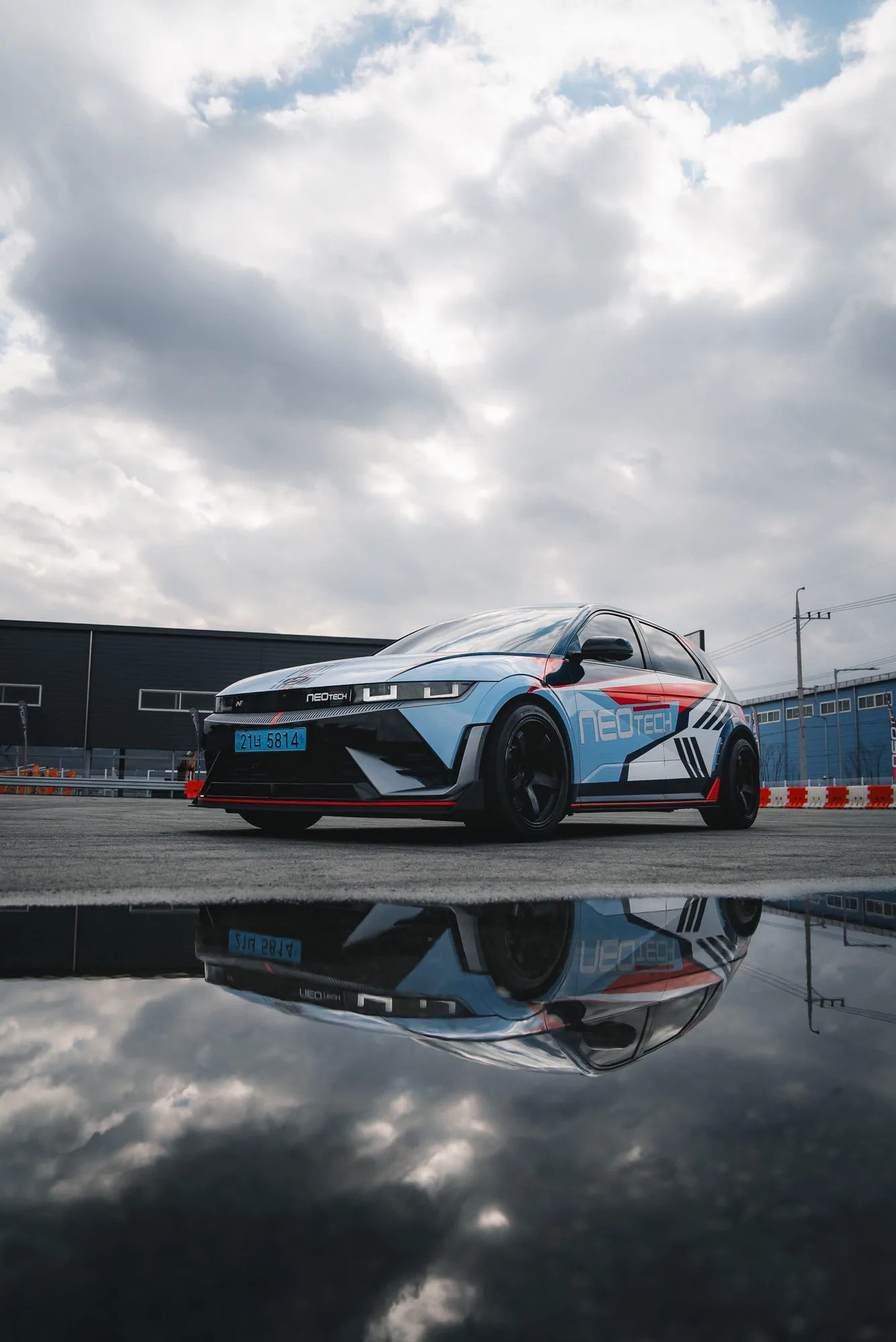 Hyundai IONIQ 5 N in NEOTECH livery reflected in a puddle at the proving ground
